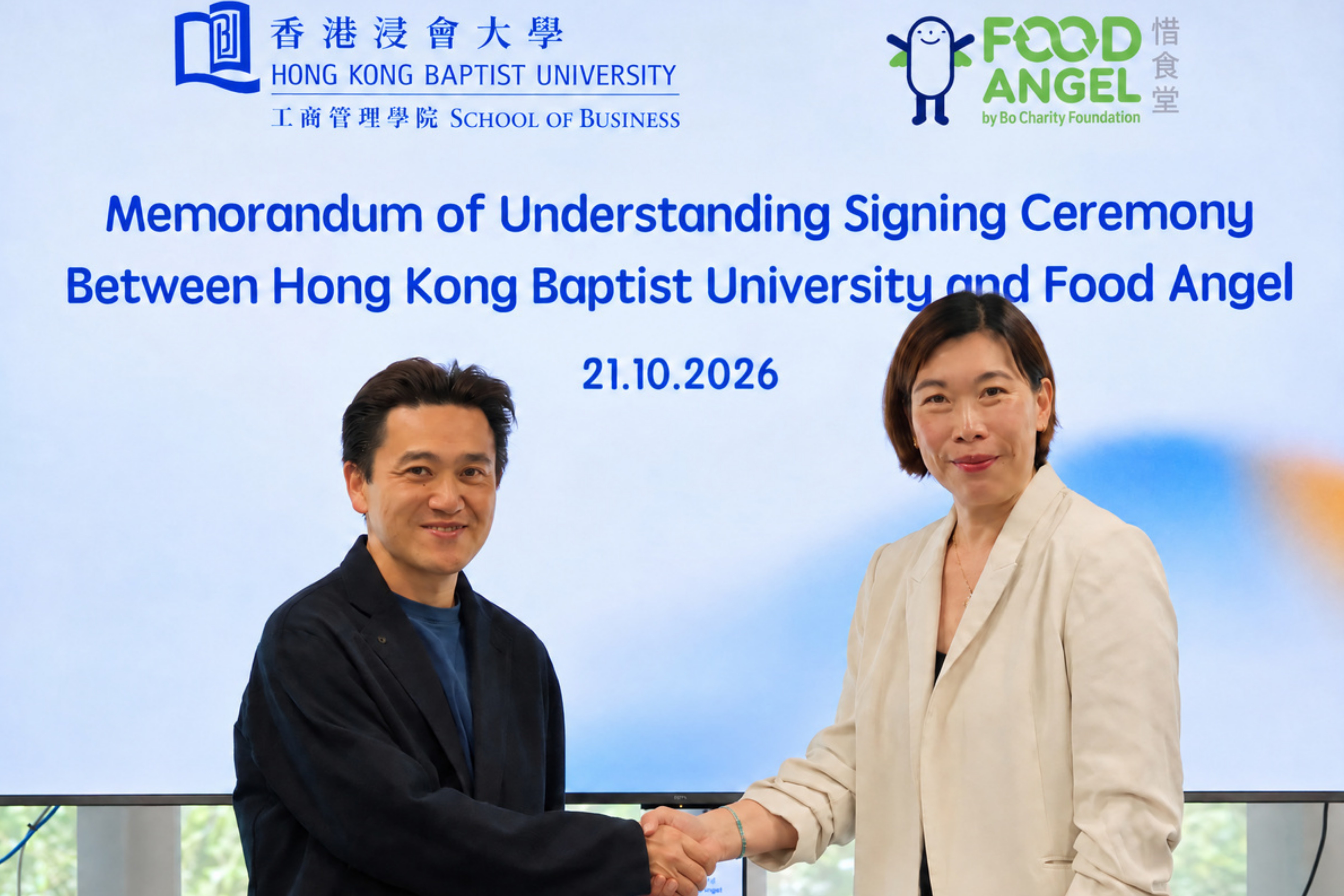 Mr Ryan Man, Acting Dean of the School of Business at HKBU (left), and Ms Astor Wong, Head of Partnership and Resources Development at Food Angel (right), shake hands following the MoU signing ceremony to establish a strategic partnership.